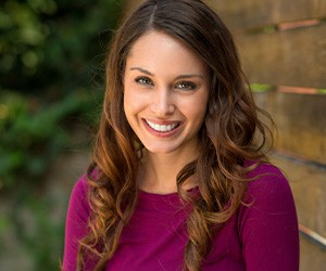 Woman sitting outside and smiling with veneers