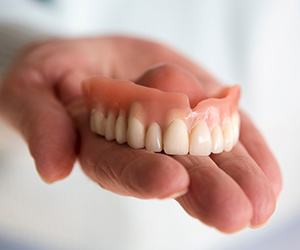 A hand holding a removable upper denture