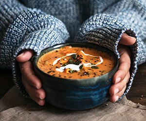 Hands holding a bowl of soup