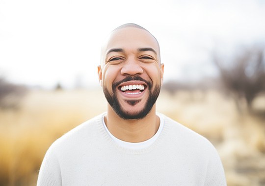 Man in white shirt smiling outside